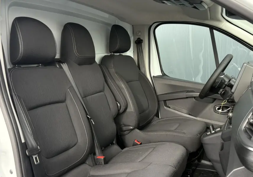 Vue intérieure côté conducteur du Renault Trafic Fourgon 2026, sièges tissu noir avec surpiqûres blanches.