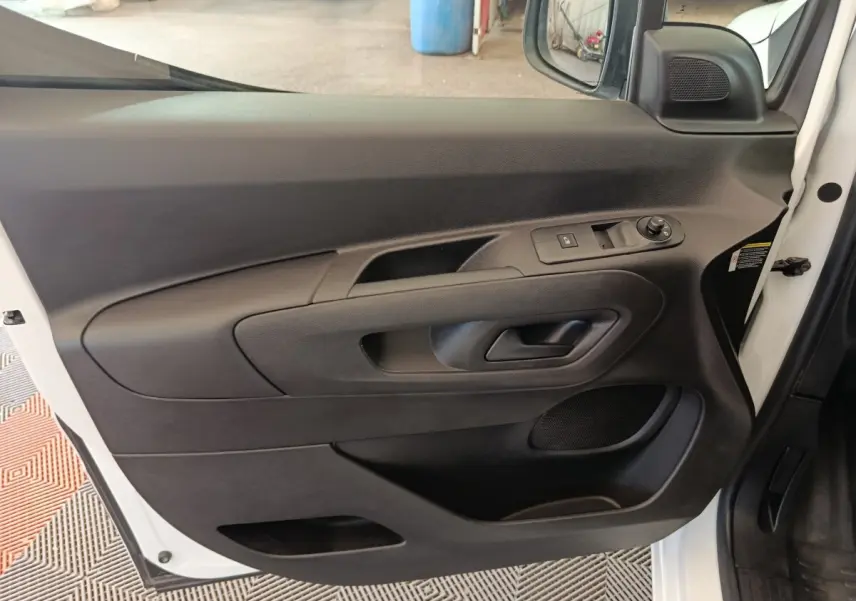 Vue intérieure côté gauche de la porte avant d’un Citroën Berlingo blanc 2021 avec commandes de vitre et miroir.