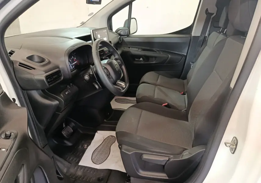Vue intérieure côté conducteur du Citroën Berlingo blanc 2021, montrant le tableau de bord et les sièges avant gris foncé.