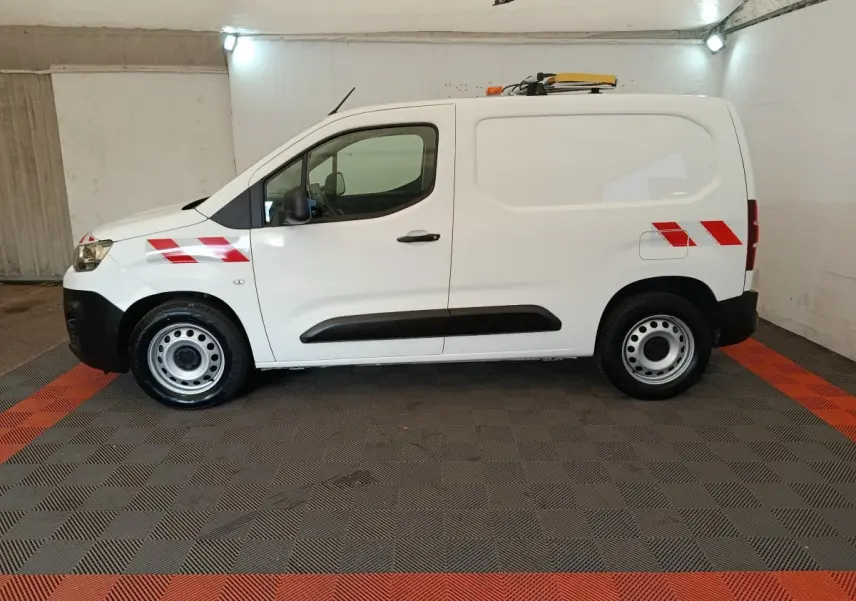 Vue de profil côté gauche d’un utilitaire Citroën Berlingo blanc 2021 avec bandes réfléchissantes rouges et gyrophare sur le toit.