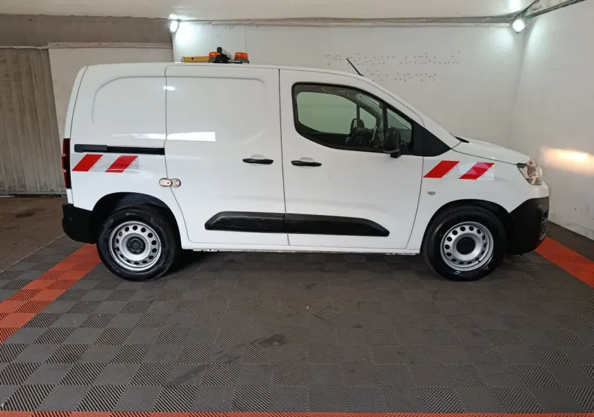 Vue de profil côté droit d'un Citroën Berlingo blanc 2021 avec bandes réfléchissantes rouges et gyrophare orange sur le toit.