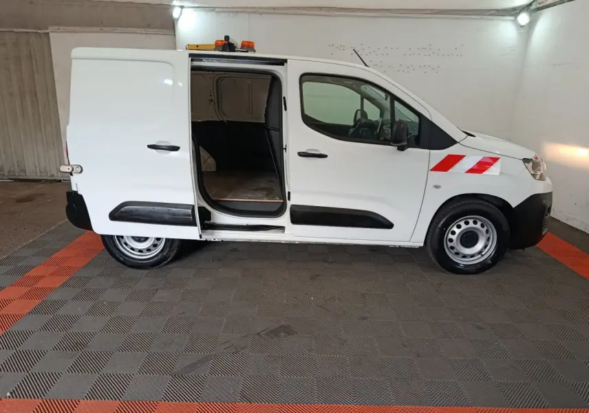 Vue de profil côté droit d’un Citroën Berlingo blanc 2021 avec porte latérale coulissante ouverte et bandes rouges réfléchissantes sur l’aile avant.