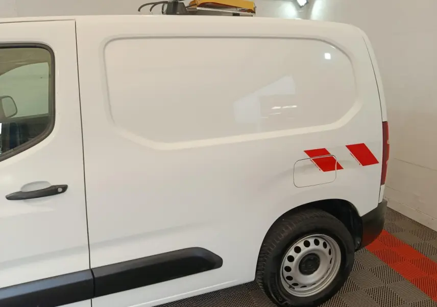 Vue latérale droite d’un Citroën Berlingo blanc 2021 avec bandes rouges réfléchissantes sur l’aile arrière.