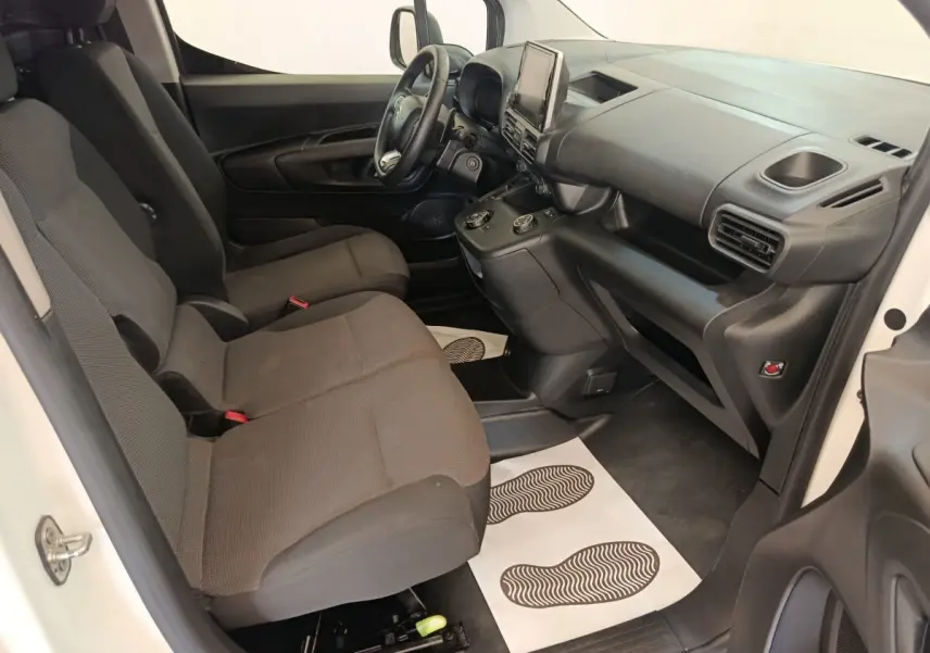 Vue intérieure côté conducteur du Citroën Berlingo blanc 2021, avec tableau de bord noir et sièges tissu gris.