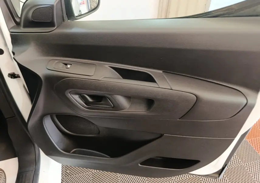 Vue rapprochée de la porte avant gauche noire du Citroën Berlingo blanc 2021 avec poignée et haut-parleur intégrés.