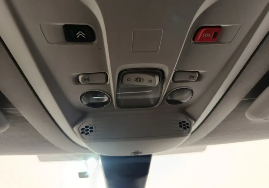 Vue en contre-plongée du plafonnier gris clair du Citroën Berlingo 2021 avec bouton SOS rouge et commandes d’éclairage.
