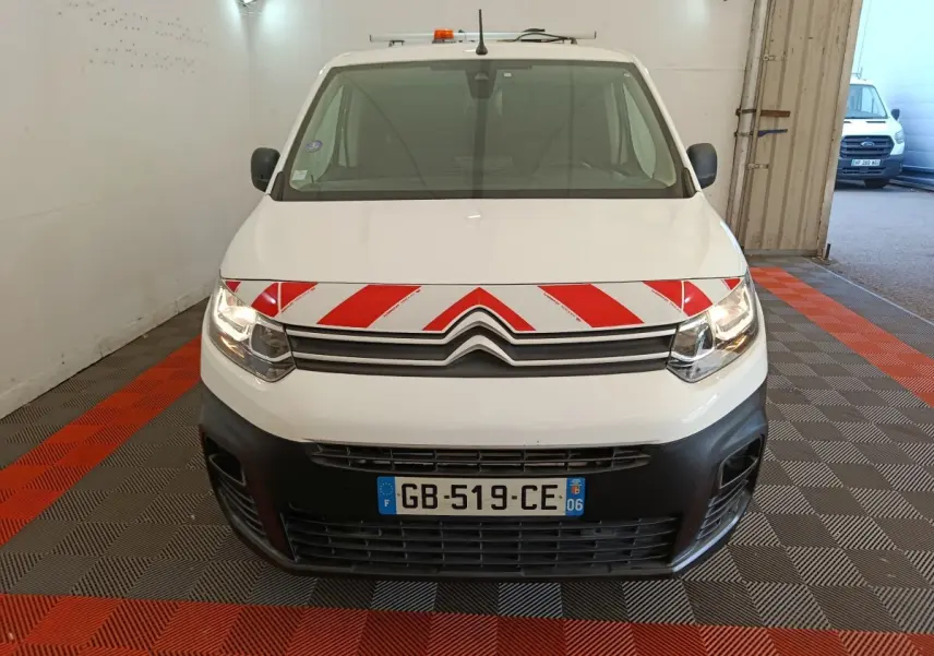 Vue avant d'un Citroën Berlingo blanc 2021 avec bande rouge et blanche réfléchissante sur le capot, en intérieur.