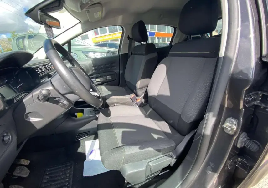 Vue intérieure côté conducteur de la Citroën C3 gris platinium, montrant les sièges avant et le volant noir.