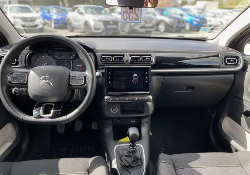 Vue intérieure avant du tableau de bord et volant de la Citroën C3 2021 avec écran tactile et boîte manuelle.
