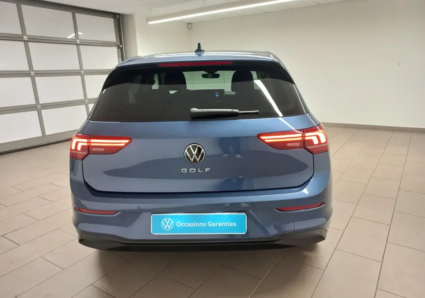Vue arrière d'une Volkswagen Golf 1.5 TSI 2025 en bleu Anemone avec feux LED allumés dans un garage.
