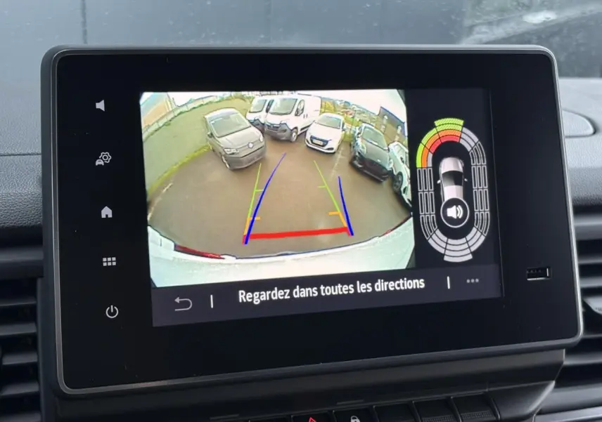 Vue de l'écran de la caméra de recul du Renault Trafic blanc, avec lignes de guidage colorées et véhicules en arrière-plan.