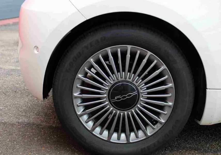Gros plan sur la roue arrière droite blanche de la FIAT 500 électrique 2023 avec jante argentée à rayons fins et logo central 500.