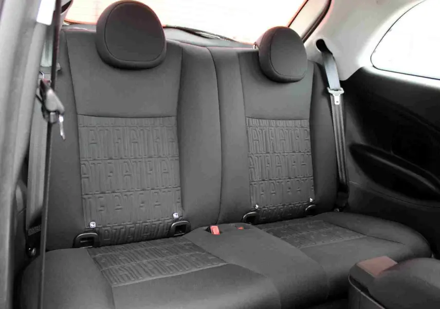 Vue intérieure sur la banquette arrière noire de la Fiat 500 électrique 2023 avec motifs texturés et ceintures visibles.