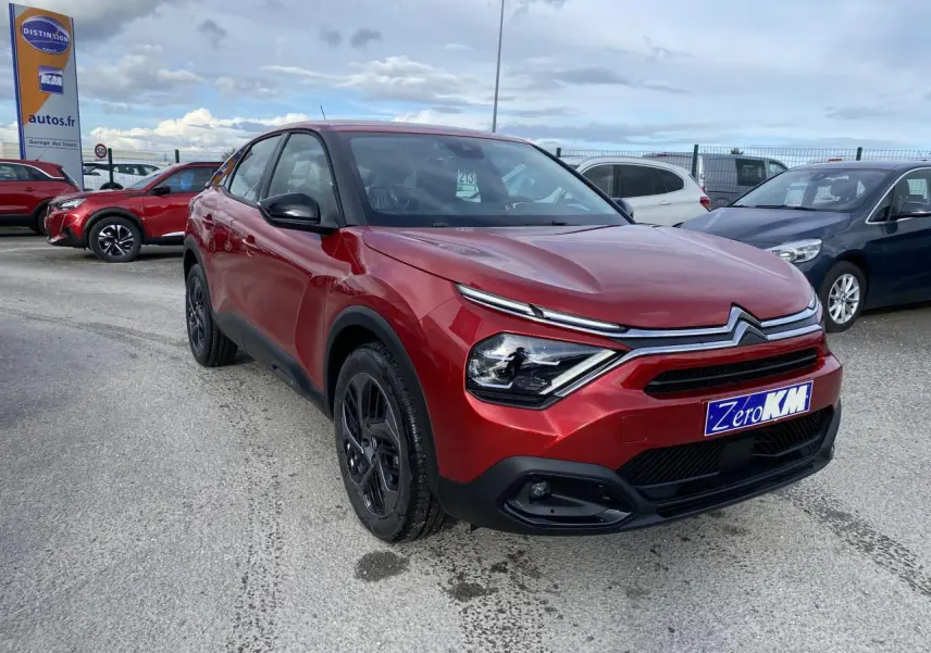Citroën C4 Rouge Elixir en 3/4 avant droit avec jantes alliage noires et calandre distinctive sur parking.