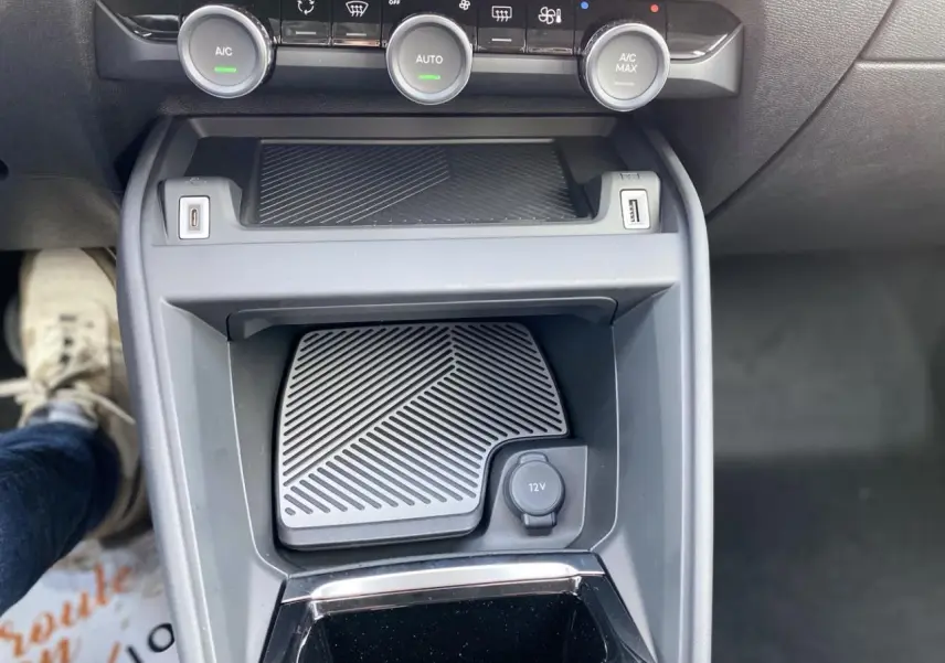 Vue rapprochée de la console centrale de la Citroën C4 2023 avec commandes climatisation et prise 12V visible.