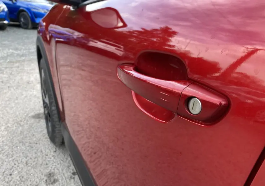 Poignée de porte côté gauche rouge Elixir nacré d'une Citroën C4 2023, avec serrure visible en gros plan.