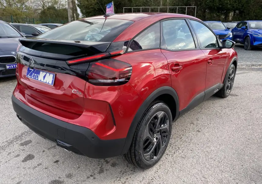 Vue 3/4 arrière droite d'une Citroën C4 2023 rouge Elixir avec jantes alliage noires et toit noir contrasté.