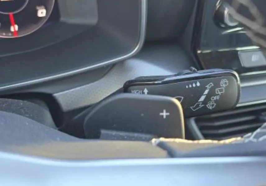 Gros plan sur la commande des essuie-glaces et la palette de changement de vitesse côté gauche du tableau de bord d'une SEAT Leon blanche.