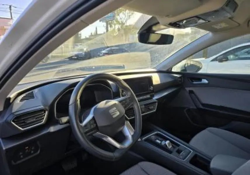 Intérieur de la SEAT LEON blanc, vue côté conducteur, avec tableau de bord moderne et volant cuir multifonction.