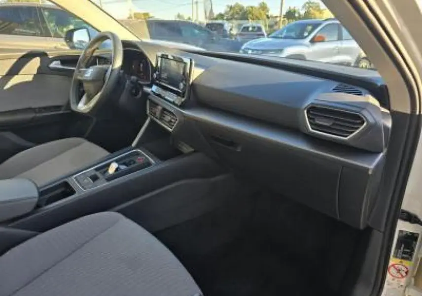 Intérieur de la SEAT LEON IV blanc, vue côté conducteur, tableau de bord moderne avec écran tactile central.