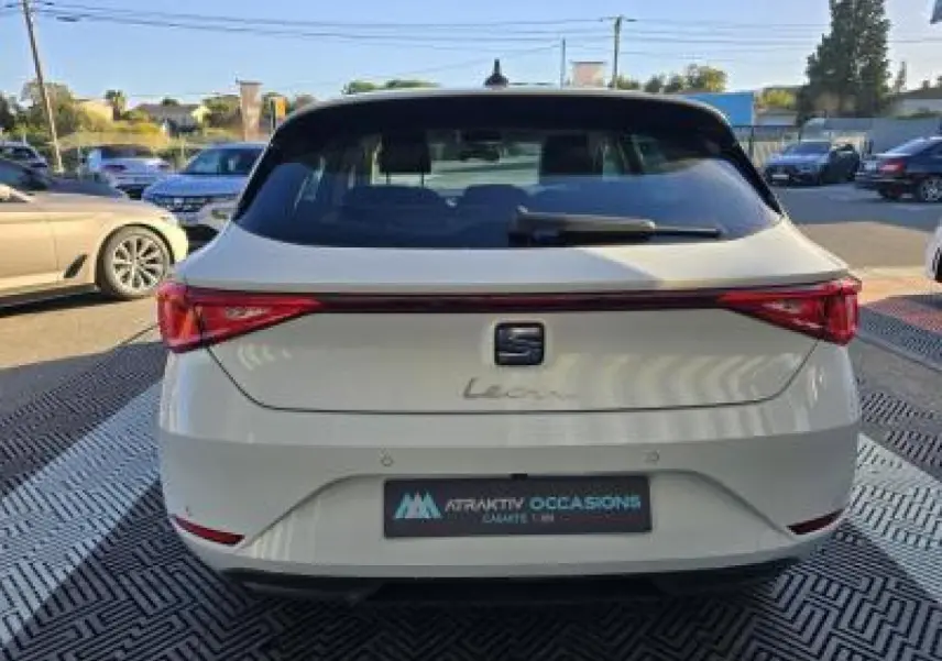 Vue arrière d'une SEAT Leon blanche 2024 avec feux arrière reliés par une bande lumineuse rouge.