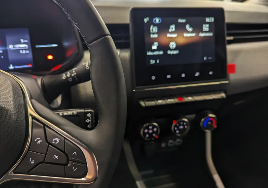 Vue intérieure rapprochée du volant et de l’écran tactile central de la Renault Clio V 2025, finition Evolution, avec commandes au volant visibles.