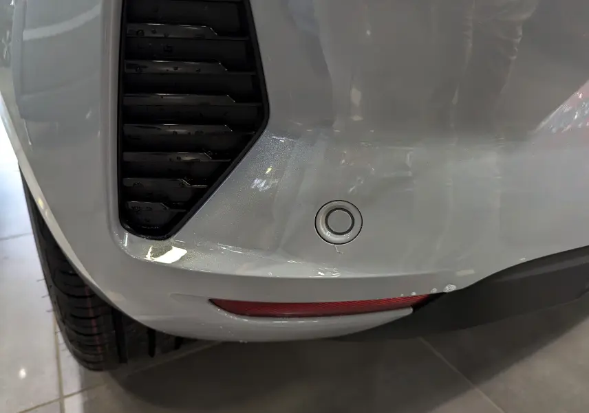 Gros plan sur le pare-chocs arrière gris Rafale de la Renault Clio V avec capteur de recul et feu réfléchissant.