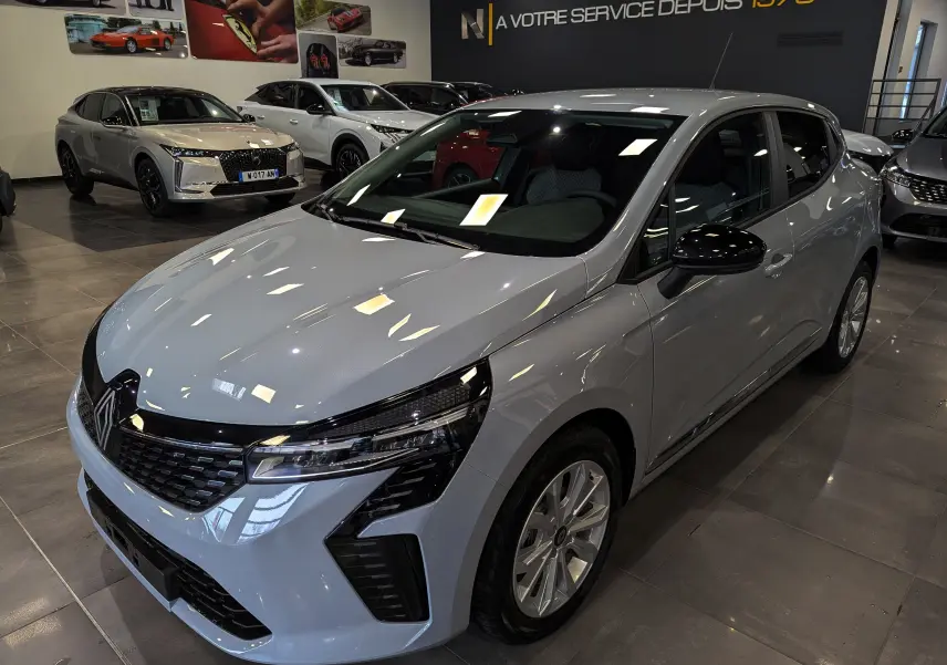 Renault Clio V Blue dCi 100 Gris Rafale en 3/4 avant droit, avec calandre noire et jantes alliage en showroom.