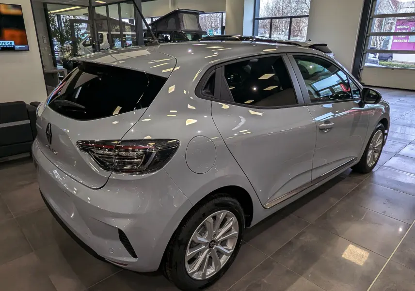 Vue 3/4 arrière droite d'une Renault Clio V gris Rafale en showroom, avec vitres teintées et jantes alliage 16 pouces.