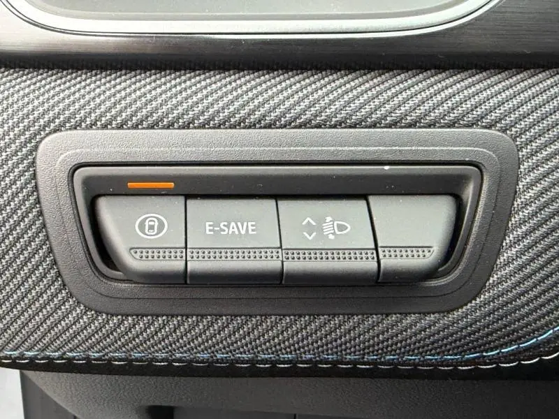 Gros plan sur les boutons de commande E-SAVE et réglage des phares sur tableau de bord carbone du Renault Captur Gris Rafale.