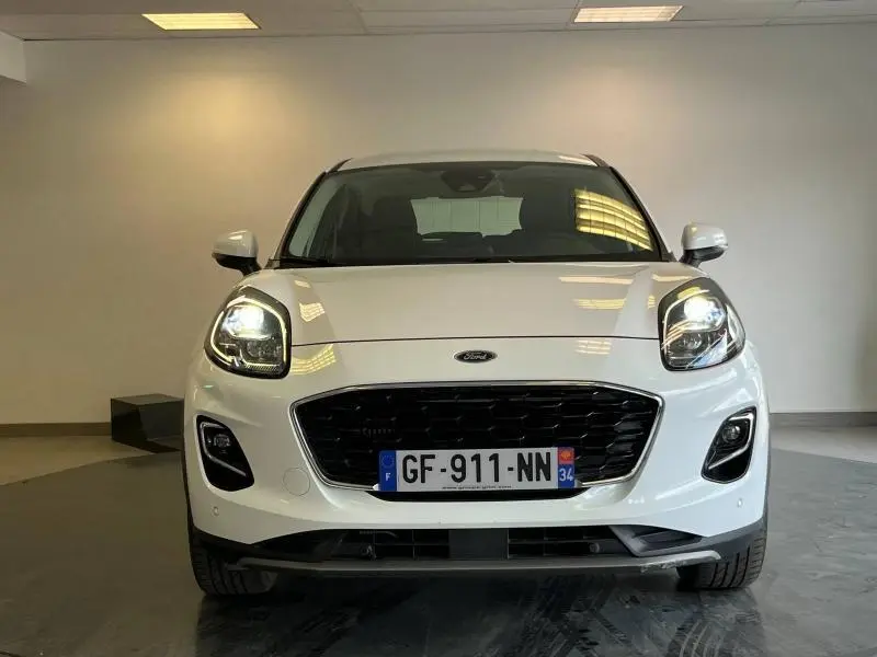 Vue frontale d'une Ford Puma blanc glacier avec phares allumés et calandre noire brillante.
