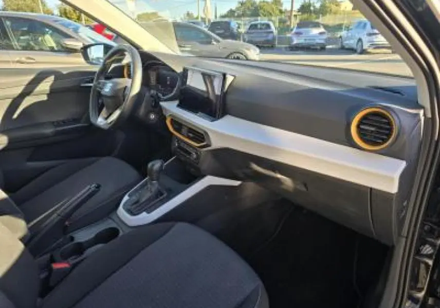 Intérieur avant droit du SEAT Arona 2024 noir minuit, avec tableau de bord bicolore et aérateurs orange.