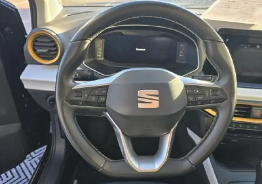 Volant sport cuir multifonction au méplat du SEAT Arona 2024 vu de face, avec tableau de bord digital en arrière-plan.