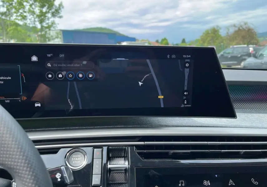 Vue intérieure du tableau de bord du Peugeot 5008 Hybrid 2025 avec écran tactile de navigation et bouton start/stop.