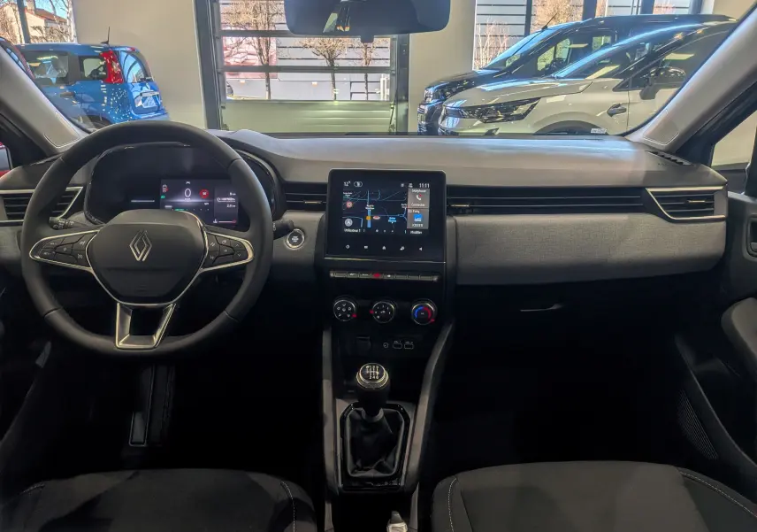 Vue intérieure avant de la Renault Clio V gris Rafale, avec tableau de bord moderne et boîte manuelle visible.