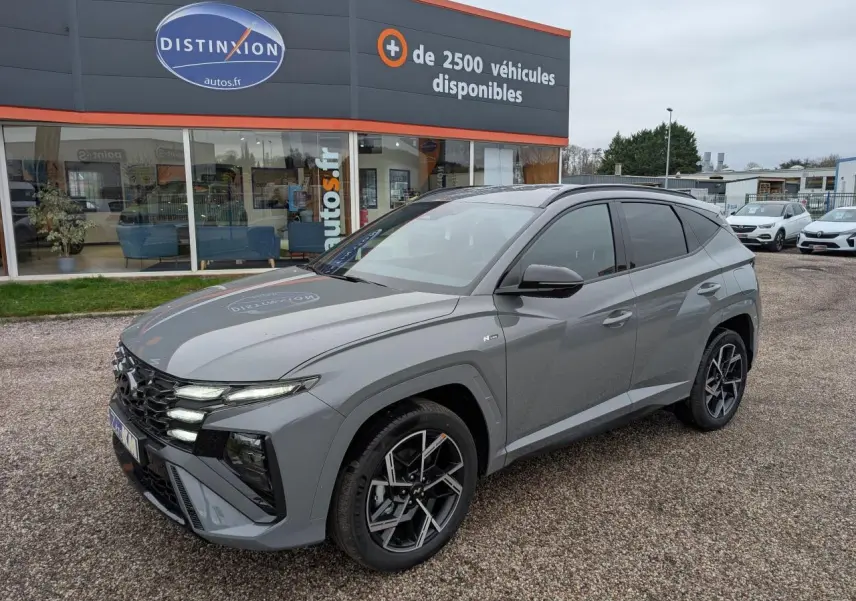 Vue 3/4 avant droite d’un Hyundai Tucson gris métallisé N Line avec jantes alliage 19 pouces et vitres teintées.