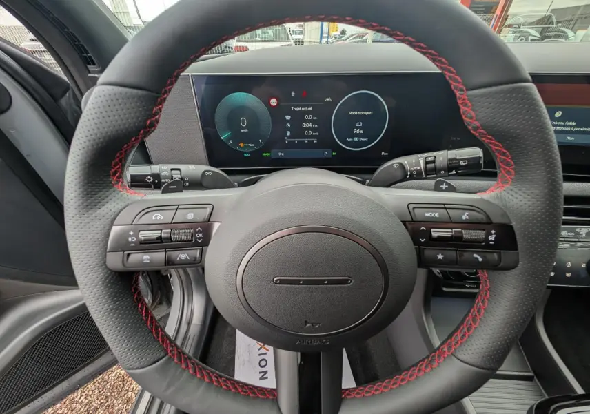 Vue centrée sur le volant cuir noir avec surpiqûres rouges et tableau de bord numérique du Hyundai Tucson gris N Line.