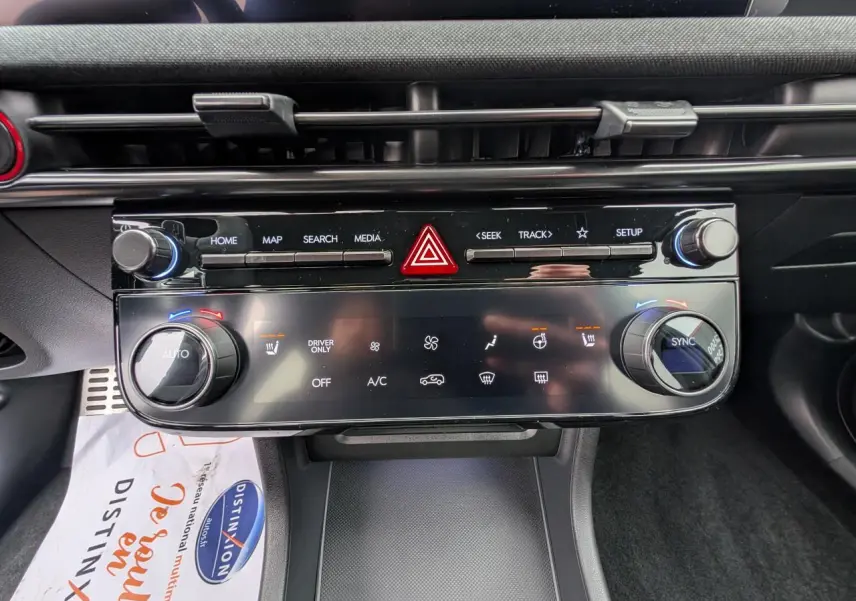 Vue rapprochée du tableau de bord noir du Hyundai Tucson gris, mettant en valeur la console centrale avec commandes climatisation et multimédia.