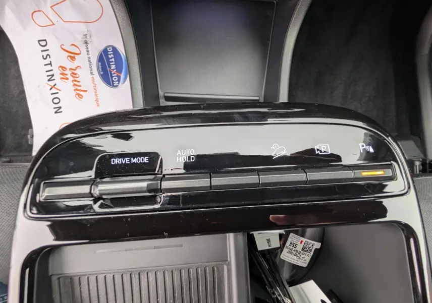 Vue rapprochée de la console centrale noire brillante du Hyundai Tucson gris, avec commandes Drive Mode et Auto Hold.