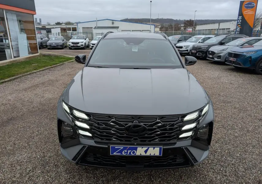 Vue frontale d’un Hyundai Tucson gris métallisé avec calandre noire N Line et feux LED allumés.