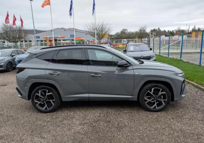Profil côté gauche d’un Hyundai Tucson gris métallisé N Line 2026 avec jantes alliage 19 pouces et vitres surteintées.