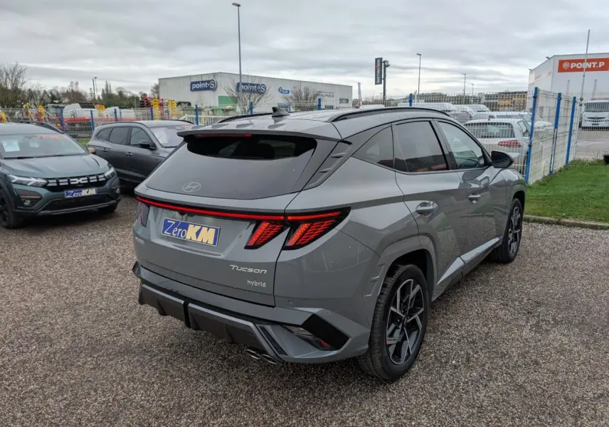 Vue 3/4 arrière droite d'un Hyundai Tucson gris métallisé avec feux arrière LED et double sortie d'échappement.