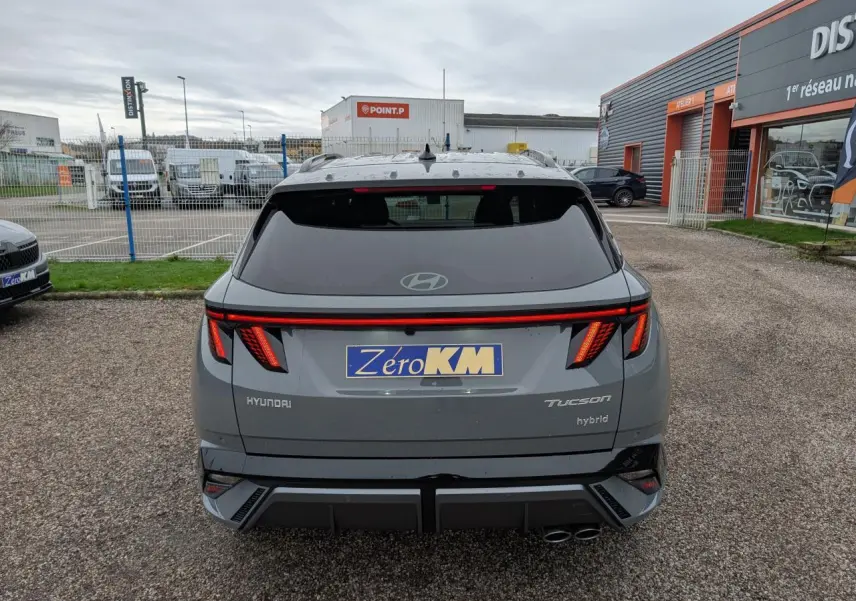 Vue arrière d’un Hyundai Tucson gris métallisé avec feux arrière LED en bandeau et double sortie d’échappement.