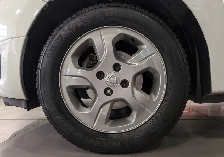 Gros plan sur la roue avant droite d'une Dacia Sandero blanc glacier, mettant en valeur le pneu et l'aile du véhicule.