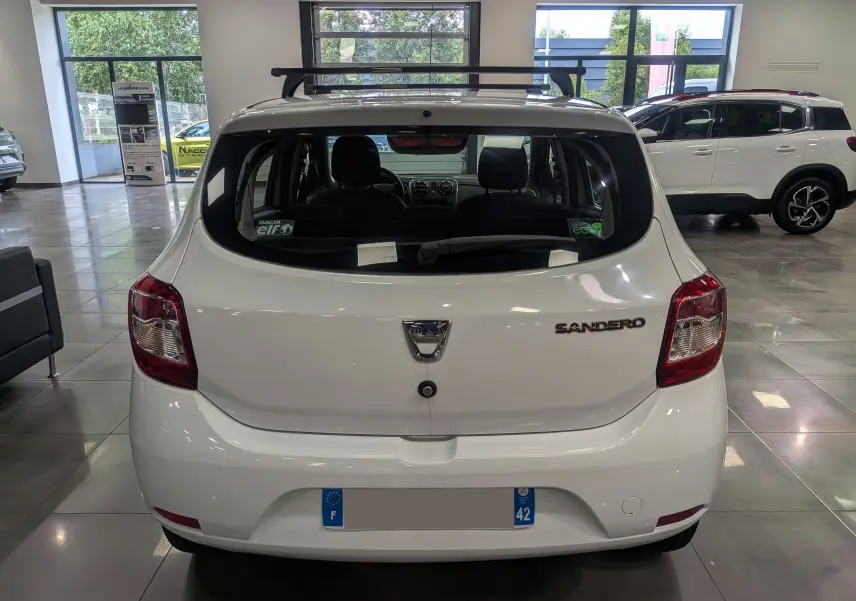 Vue arrière d'une Dacia Sandero blanc glacier en showroom, avec logo et badge modèle bien visibles.