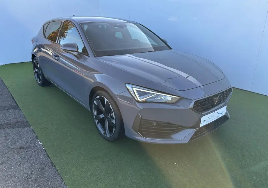Vue 3/4 avant d'une CUPRA Leon 2024 gris Graphene avec jantes alliage noires et feux LED distinctifs.