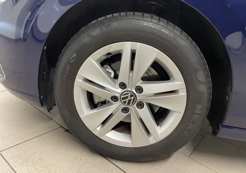 Gros plan sur la roue avant gauche d'une Volkswagen Golf 2023 bleu Atlantique avec jante en alliage à cinq branches.