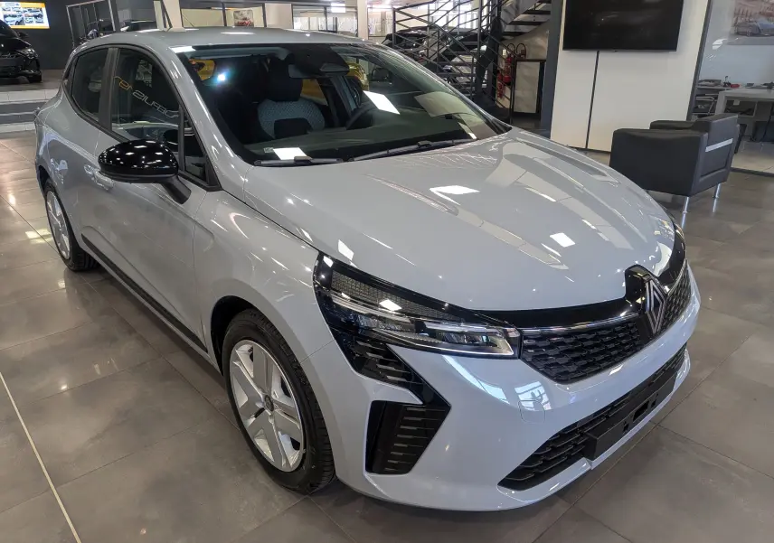 Renault Clio V Blue dCi 100 en gris Rafale, vue 3/4 avant gauche, avec calandre noire et jantes alliage.