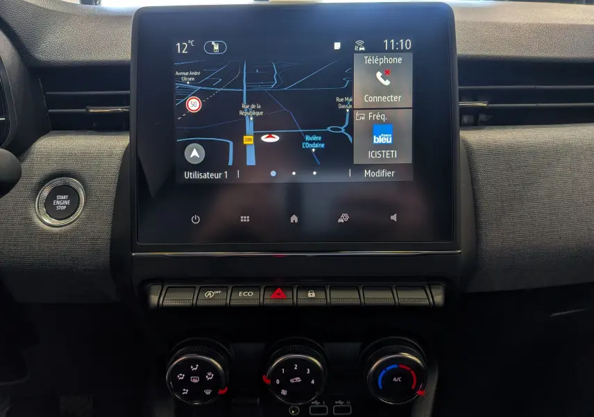 Vue rapprochée de l’écran tactile central et des commandes de climatisation du Renault Clio V Gris Rafale, intérieur noir.