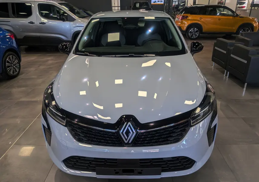 Vue avant d'une Renault Clio V gris Rafale en showroom, avec calandre noire et logo central visible.